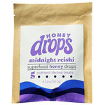 A jar of Eat Honey Drops Midnight Reishi supplement with reishi mushroom extract and honey, displayed on a wooden surface.