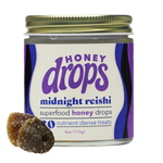 Dark, glossy Midnight Reishi supplement capsules from Eat Honey Drops displayed in a clear container.